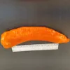 A long orange pepper, approximately 8 inches in length, resting on a dark surface next to a ruler for scale.